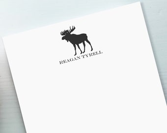 May include: Black and white silhouette of a moose with the text "REAGAN TYRELL" below it.