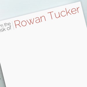 May include: White stationery with the text "from the desk of Rowan Tucker" in red lettering.