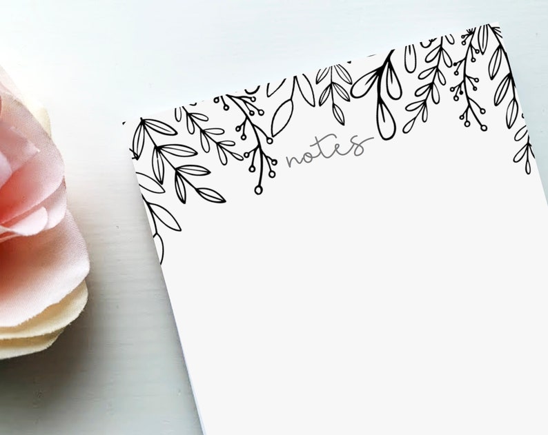 May include: A white notepad with a black floral border and the word "notes" written in gray text.