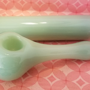 Peut inclure: Une pipe en verre vert clair avec un bol arrondi et un long manche fin. La pipe est livrée avec un tube de rangement en verre vert clair assorti avec un bouchon en liège.