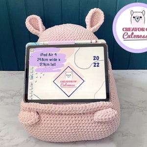 May include: A pink crocheted llama-shaped stand for an iPad Air 4. The stand is 24.8 inches wide and 17.9 inches tall. The iPad is displaying a digital planner with the text "CREATOR OF Cuteness" on the screen.