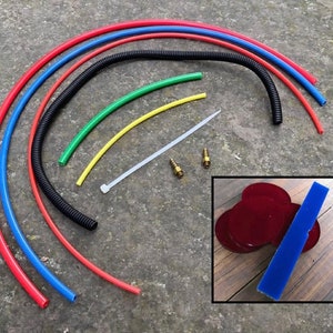 May include: Assortment of colourful tubing, a black coiled hose, a white cable tie, two brass fittings, and three red felt circles and a blue felt rectangle.
