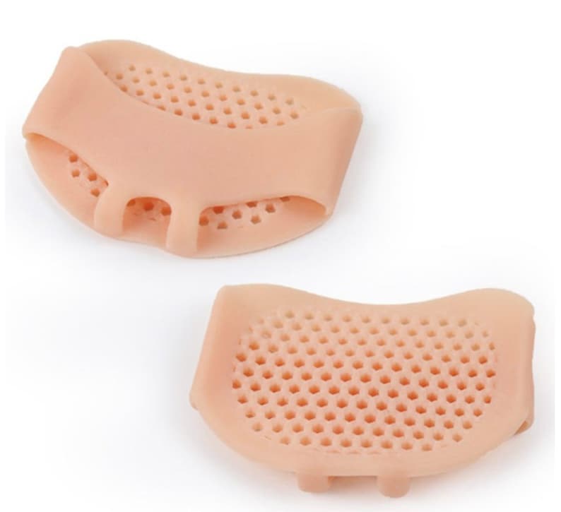 May include: Two beige silicone metatarsal pads with a honeycomb design. Each pad has a loop for the second toe and a small section for the third and fourth toes. The pads are designed to cushion the ball of the foot.