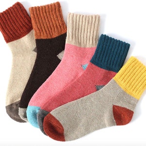 May include: Five pairs of colorful socks with ribbed cuffs and contrasting toe and heel colors. The socks feature a variety of colors, including orange, brown, pink, teal, and yellow. The socks are made of a soft, knitted material.