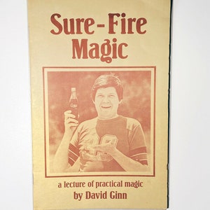 Puede incluir: Portada de libro vintage con el título "Sure-Fire Magic" en fuente marrón rojizo. La portada muestra a un hombre sosteniendo una botella de Coca-Cola. El texto "a lecture of practical magic by David Ginn" está impreso en la parte inferior.