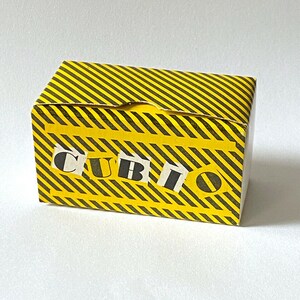May include: A yellow and black striped box with the word "CUBIO" printed on the front in black letters.