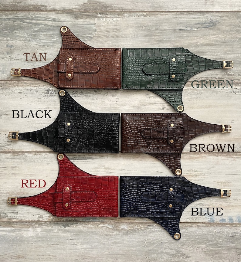 May include: Five leather belts with different coloured crocodile embossed patterns. The belts are labelled "TAN", "GREEN", "BLACK", "BROWN", and "BLUE".