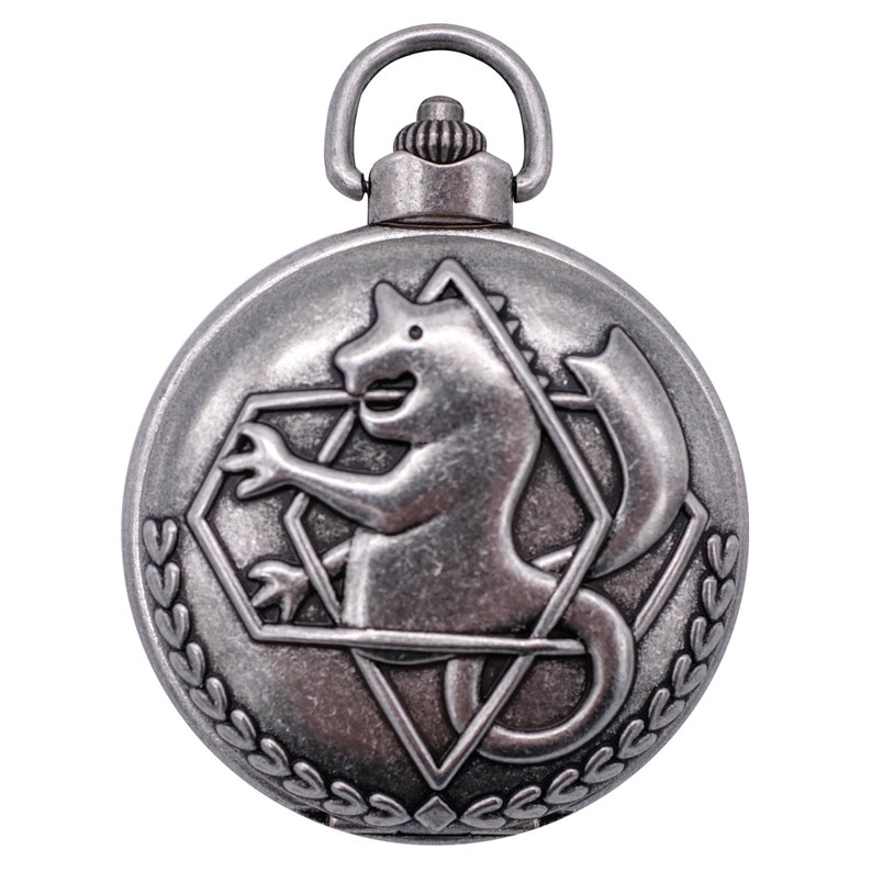 May include: A silver pocket watch with a detailed design of a mythical creature with a sword, surrounded by a diamond shape and a laurel wreath.