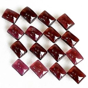 May include: A collection of fifteen rectangular, deep red garnet gemstones arranged in a grid pattern. Each stone features a smooth, polished surface with a reflective finish, showcasing a consistent dark crimson hue and uniform rectangular shape.