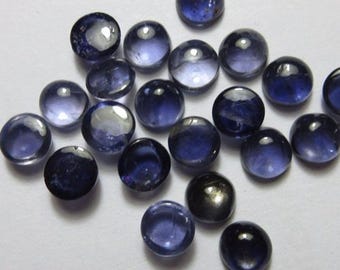 May include: A collection of polished, round, blue gemstones. The stones vary in shades of blue, from light to deep indigo, with a glossy, reflective surface. The arrangement is scattered, showcasing the individual gems.