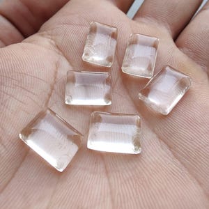 May include: Six clear, rectangular glass tiles with rounded edges are displayed. The tiles are transparent, allowing light to pass through. The tiles are arranged on a light-colored surface.