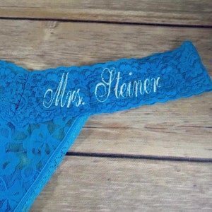 Könnte beinhalten: Blaue Spitzenunterwäsche mit weißer Stickerei, die "Frau Steiner" lautet.