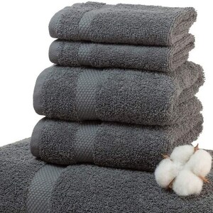 May include: A stack of six charcoal gray bath towels with a textured stripe design. A sprig of white cotton is placed on top of the towels. The towels are soft and fluffy, perfect for a bathroom.
