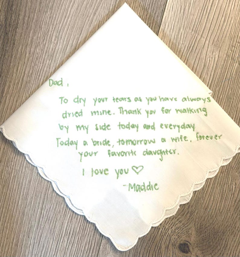 K&ouml;nnte beinhalten: Ein wei&szlig;es Taschentuch mit gewelltem Rand und gr&uuml;ner Stickerei, die folgenden Text enth&auml;lt: Dad, To dry your tears as you have always dried mine. Thank you for walking by my side today and everyday. Today a bride, tomorrow a wife, forever your favorite daughter. I love you -Maddie.