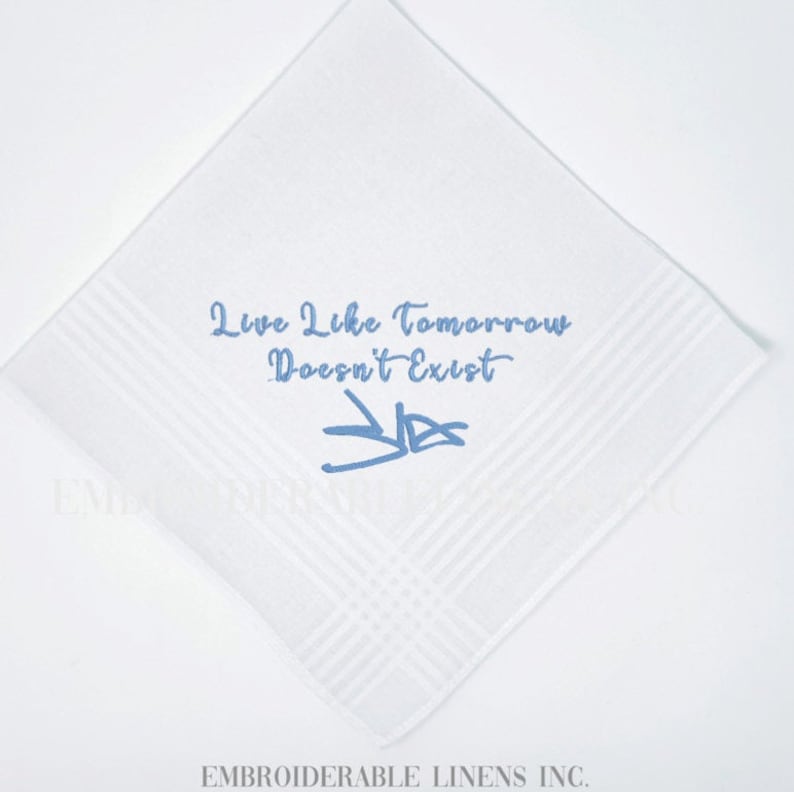 K&ouml;nnte beinhalten: Ein quadratisches wei&szlig;es Taschentuch mit hellblauer Stickerei. Der Text "Live Like Tomorrow Doesn't Exist" ist in Schreibschrift &uuml;ber einer stilisierten hellblauen Signatur gestickt. Der Stoff hat ein dezentes gestreiftes Randmuster.