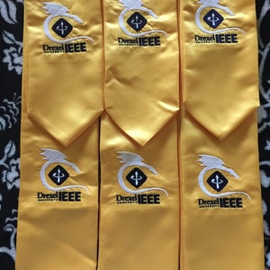 May include: Six yellow graduation stoles with a white dragon and the text "Drexel University IEEE" embroidered on each.