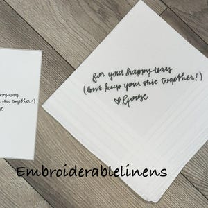 K&ouml;nnte beinhalten: Ein wei&szlig;es quadratisches Taschentuch und eine passende rechteckige Karte, beide mit schwarzem kursivem Text: for your happy tears (but keep your shit together!) mit einem Herzsymbol und dem Namen George unter dem Text.