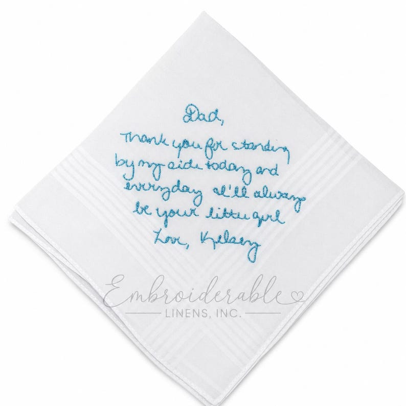 K&ouml;nnte beinhalten: Ein quadratisches wei&szlig;es Taschentuch mit blauem, in Schreibschrift gesticktem Text: Dad, thank you for standing by my side today and everyday I'll always be your little girl Love, Kelsey. Der Stoff hat ein dezentes gestreiftes Randmuster.