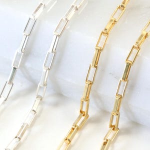 Puede incluir: Dos collares de cadena delicados, uno en tono plateado pulido y otro en tono dorado pulido. Cada collar presenta una serie de eslabones rectangulares alargados conectados en un patrón repetitivo para formar una cadena fina y continua.