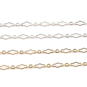 May include: Three chains, one silver and two gold, with a delicate, open-link design. The chains are laid out horizontally on a white background.