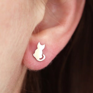 May include: A pair of silver cat stud earrings. The earrings are small and delicate, and they feature a simple silhouette of a cat.