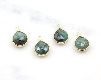 May include: Four gold-plated teardrop-shaped pendants with green gemstone inserts.