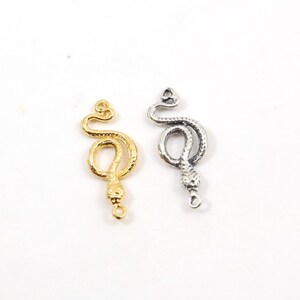 Peut inclure: Deux breloques en métal en forme de serpent, l'une dorée et l'autre argentée, avec une boucle en bas pour les attacher à des bijoux ou d'autres objets artisanaux.