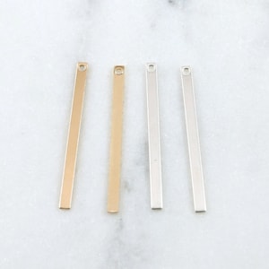 May include: Four metal bar pendants, two gold and two silver, with a hole at the top for attaching to jewelry.