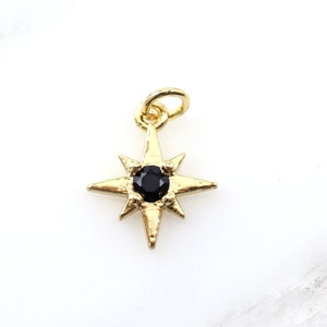 May include: Gold-toned star charm with a black gemstone in the center. The charm has a loop at the top for attaching to a necklace or bracelet.