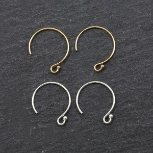 May include: Four earring hoops, two gold and two silver, on a black background.