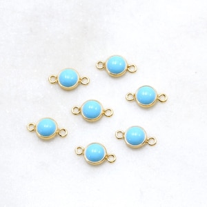 May include: Six gold-toned connector charms with light blue round cabochon stones. Each charm has two jump rings for attaching to jewelry.