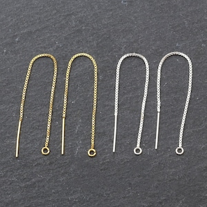 May include: Four earring findings, two gold and two silver, with a chain and a small loop at the end.
