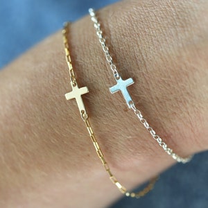 May include: Two delicate chain bracelets with small cross charms. One bracelet is gold and the other is silver.