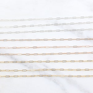 May include: A set of six delicate chain necklaces in silver, gold, and rose gold. The chains are made of small, linked oval shapes.