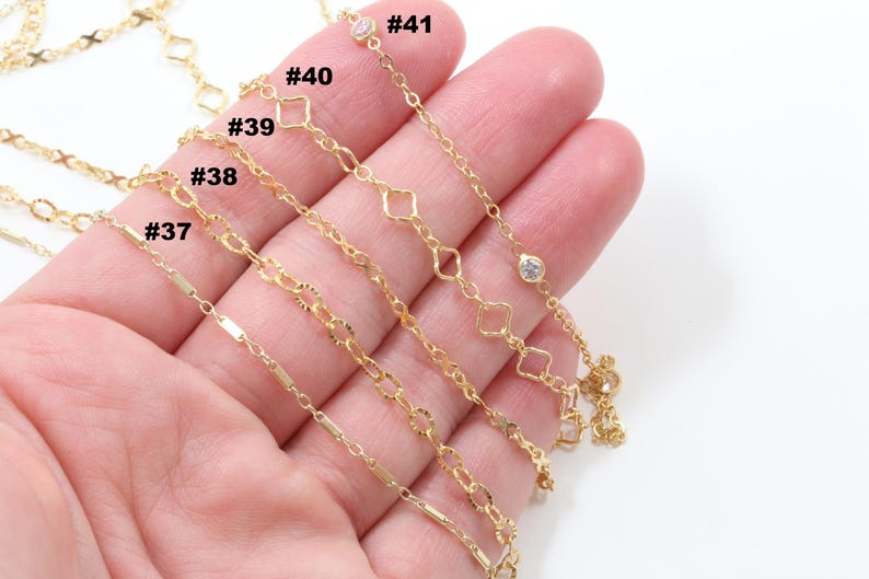 Peut inclure: Plusieurs colliers dor&eacute;s avec diff&eacute;rents mod&egrave;les de cha&icirc;nes, notamment des maillons en forme de barre, ovales et en losange. Certains colliers comportent de petites pierres pr&eacute;cieuses transparentes. Les colliers sont pr&eacute;sent&eacute;s sur un fond clair.