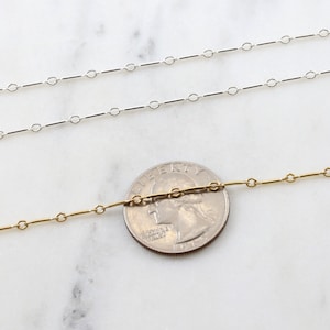 Puede incluir: Dos cadenas, una plateada y otra dorada, se colocan sobre una superficie de m&aacute;rmol blanco. Una moneda de 25 centavos de d&oacute;lar estadounidense se coloca entre las cadenas para mostrar la escala.