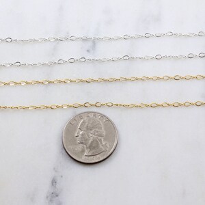 May include: Three gold and silver chains laid out on a white marble surface. A US quarter is placed below the chains for size comparison.