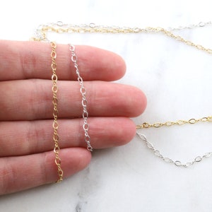 May include: Three chains of different lengths, one gold, one silver, and one silver with a twisted design. The chains are laid out on a hand, showing the different lengths and styles.