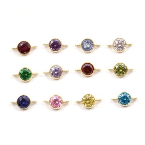 May include: Twelve gold-toned round connector charms with different colored crystal stones. The stones are red, purple, blue, clear, green, dark blue, pink, yellow, and light blue.