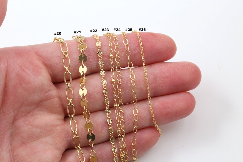 Peut inclure: Plusieurs colliers cha&icirc;ne dor&eacute;s de diff&eacute;rents styles, dont des maillons ovales, des disques et des cha&icirc;nes d&eacute;licates. Les colliers sont pr&eacute;sent&eacute;s sur un fond blanc, mettant en valeur leurs diff&eacute;rentes textures et motifs. Chaque cha&icirc;ne est num&eacute;rot&eacute;e.
