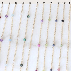 Peut inclure: Une collection de colliers d&eacute;licats en cha&icirc;ne dor&eacute;e, chacun orn&eacute; d'une seule pierre pr&eacute;cieuse. Les pierres pr&eacute;cieuses varient en couleur, notamment rouge, violet, bleu, vert et turquoise. Les colliers sont pr&eacute;sent&eacute;s sur une surface blanche.