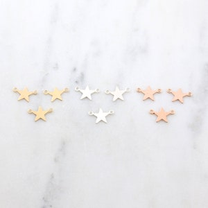 May include: Three sets of star-shaped charms with jump rings. The charms are gold, silver, and rose gold.