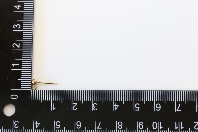 May include: A gold-toned earring finding with a small ball at the top and a straight post.