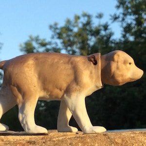 以下が含まれることがあります： 歩いている茶色と白のセラミック製のクマの置物。クマは茶色の体と白い脚と足を持っています。クマは木製の表面に立っています。