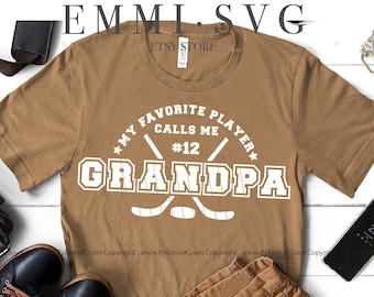 May include: A black and white graphic design of a hockey stick and puck with the text "My Favorite Player Calls Me #12 Grandpa". The design is on a white background. The graphic is for digital download and includes SVG, PNG, EPS, and DXF files.