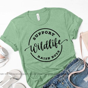 May include: A green t-shirt with a black circle graphic that says "Support Wildlife Raise Boys".
