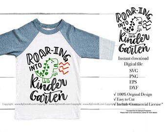 Könnte beinhalten: Ein weißes T-Shirt mit einem blau-weiß gestreiften Ärmel, das ein schwarzes und grünes Dinosaurier-Motiv mit dem Text "Roar-ing into Kindergarten" zeigt.