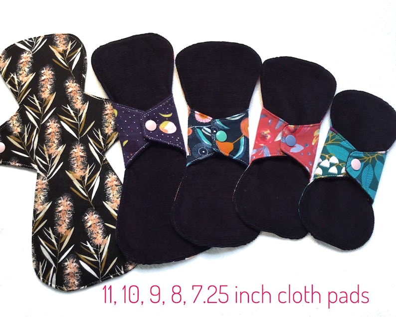 May include: Five reusable cloth pads in various sizes, ranging from 7.25 inches to 11 inches. The pads are black with colorful floral patterns and have snap closures.