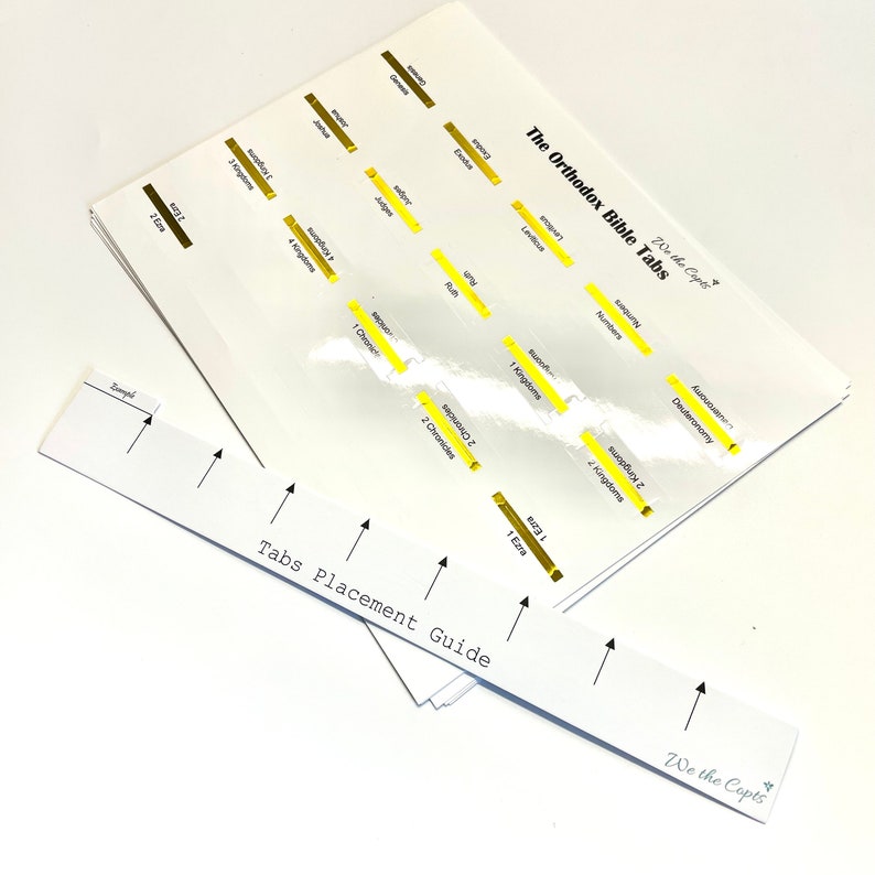 May include: A white sheet of paper with a guide for placing Bible tabs. The guide lists the books of the Bible in order, with arrows pointing to where each tab should be placed. The text "We the Copts" is printed at the bottom of the guide.