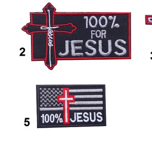 Pode incluir: Cinco patches bordados com um tema cristão. Os patches apresentam uma cruz, as palavras "100% para Jesus" e uma bandeira americana.